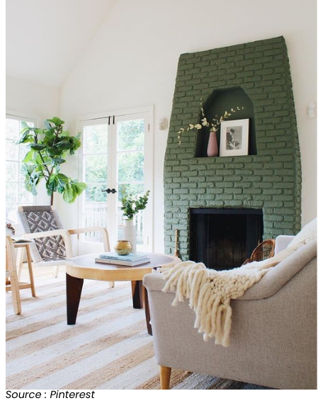 Salon lumineux avec cheminée en briques peintes en vert, meubles modernes, et plantes d'intérieur, par Pinterest.