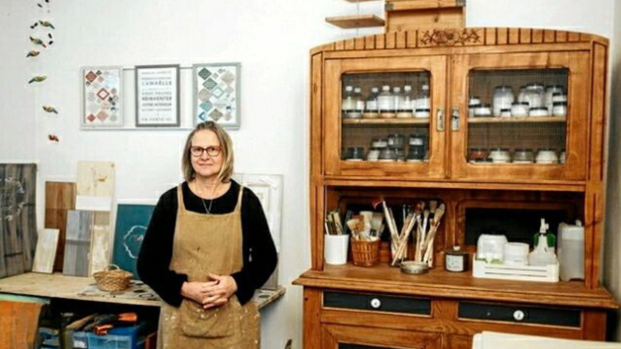 Artisan de Patine et Boisette dans son atelier, entourée de meubles en bois revalorisés et d'échantillons de peinture.